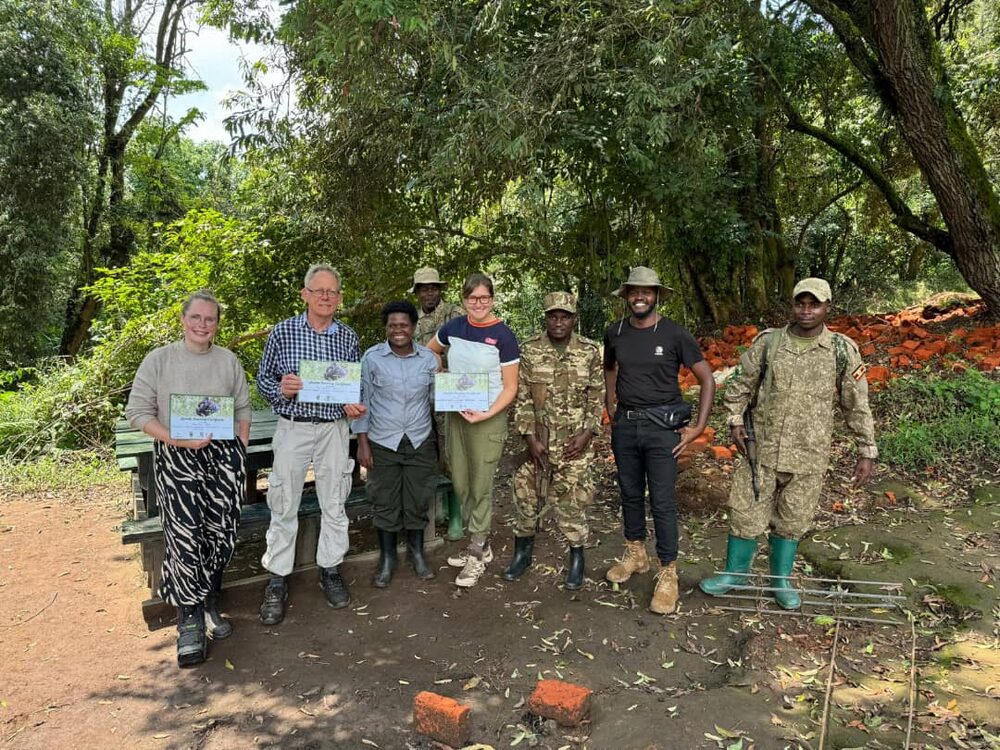Travellers holding their gorilla tracking certificates with the ranger team after a trek in Bwindi